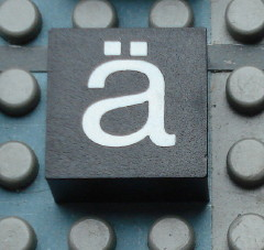 Modulex, Tile 2 x 2 (no Internal Supports) with White Lowercase Letter a with Diaeresis (ä) Pattern