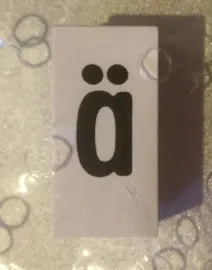 Tile, Modified 1 x 2 x 5/6 Stud Hole in End with Black Lowercase Letter a with Diaeresis (ä) Pattern