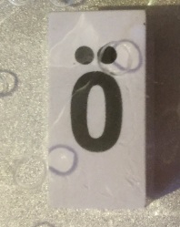 Tile, Modified 1 x 2 x 5/6 Stud Hole in End with Black Lowercase Letter o with Diaeresis (ö) Pattern