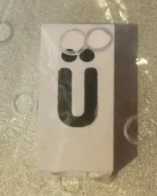 Tile, Modified 1 x 2 x 5/6 Stud Hole in End with Black Lowercase Letter u with Diaeresis (ü) Pattern