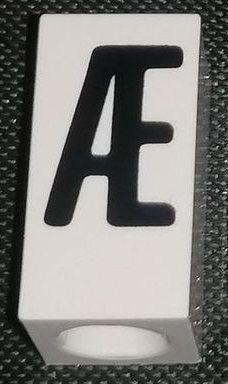 Tile, Modified 1 x 2 x 5/6 Stud Hole in End with Black Capital Ligature Æ Pattern