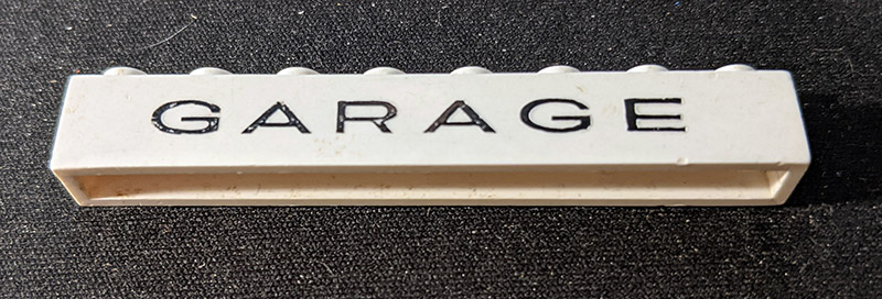 Brick 1 x 8 without Bottom Tubes with Cross Side Supports with Black 'GARAGE' Thin (Letters Wide) Pattern